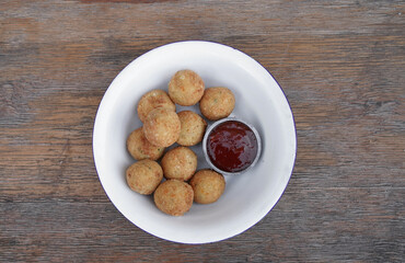 Fritters. Top view of potato and mozzarella cheese croquettes with sweet chili dipping sauce, in a white bowl on the wooden table. 