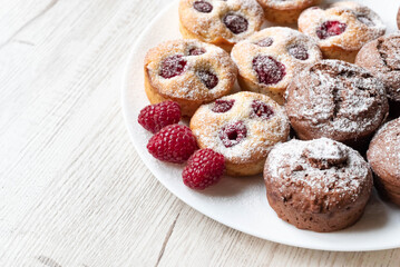 On a light table, a blurred image of raspberry and chocolate muffins. The concept of carbohydrate products.