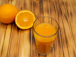 Ripe bio oranges and a glass of fresh squeezed orange juice on wooden background