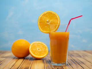 Ripe bio oranges and a glass of fresh squeezed orange juice on wooden background
