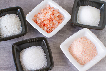 Different kinds of salt in small black and white bowls