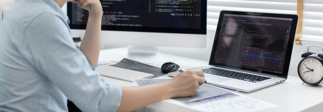 Professional development programmers are laying out a structure or draft on paper in preparation for coding on a computer, Write information or code for the website,  HTML, javascript, Software.
