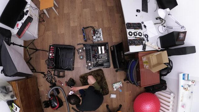 Man is assembling personal computer looking instruction on smartphone filmed from above in timelapse. Top view of Caucasian male person installing details into system unit. Home master building pc
