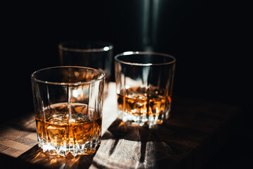 Three transparent shorts of whiskey on the table making sun reflection.