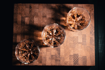 Three transparent shorts of whiskey on the table making sun reflection.