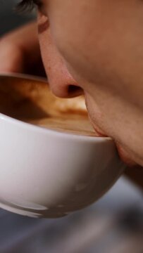 A close up of a young man enjoying a sip of coffee