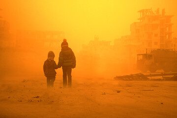 Two homeless little girl walking in ruined city