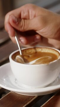 A close up of a hand stirring coffee 