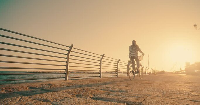 Carefree woman with bike riding on beach having fun, on the seaside promenade on a summer day. Summer Vacation. Travel and lifestyle Concept.	