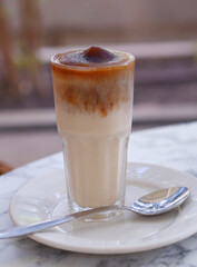 cold ice coffee in glass with cream and straw close up photo on cafe table