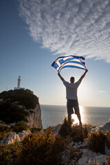 man with greece flag looking at sunset above the sea