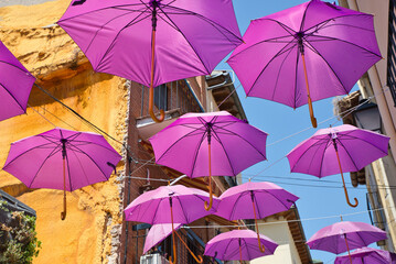 Fototapeta na wymiar Pink Umbrellas over the city. Umbrellas in the sky, colorful view. Supporting breast cancer.