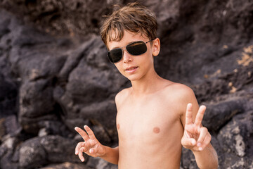funny portrait of young shirtless man wearing sunglasses in an exotic beach