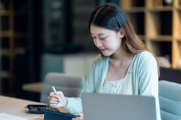 Young Business Asian woman sitting at a desk with a laptop and working in the home office or her workplace, accountant tax contract report analysis document data Audit concept.