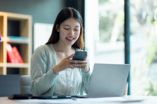 Young Business Asian woman talking on a smartphone and working in a home office. Asian female Business sitting at his workplace.