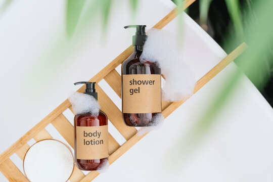 shower gel and body lotion on wooden tray on bathtub, top view