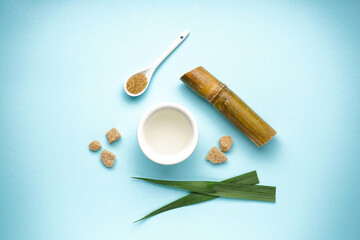 Sugar cane juice and brown sugar on blue background. Top view.