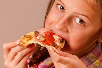 Kids' pizza. Young beautiful child girl bites slice of pizza.