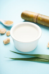 Sugar cane juice and brown sugar on blue background. Verticaly.