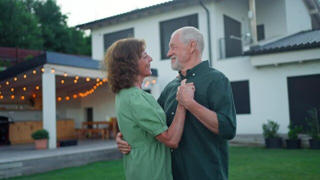 Senior woman nad man dancing together in a garden in summer
