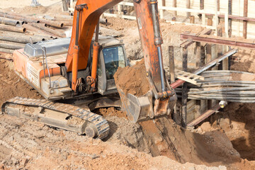 Fototapeta premium The excavator is working on a city construction site. Repair and construction concept.