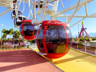 on the Ferris wheel there are large cabins for skiing tourists of red color with black, tinted windows to protect from the sun's rays. boarding tourists