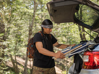 Fototapeta premium Indigenous young man unloading a car in nature