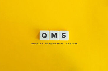Quality Management System (QMS) Banner. Block Letter Tiles on Yellow Background. Minimal Aesthetics.
