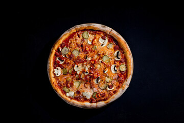 Appetizing pizza with hunting sausages, mozzarella cheese, pickled cucumbers, chili peppers on a tomato base. Mexican pizza. Top view