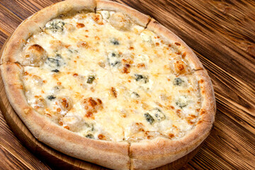 Pizza with four cheeses, mozzarella, blue cheese, Parmesan cheese. Italian cuisine. On a wooden background. View from above.