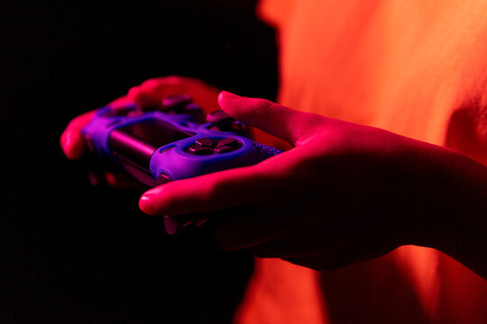 Crop female gamer under neon light