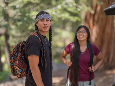 Indigenous friends unloading camping gear in nature