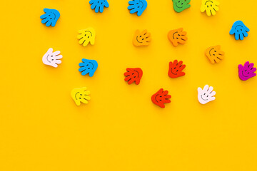 Colored wooden figures in the form hand with smiles on a yellow background