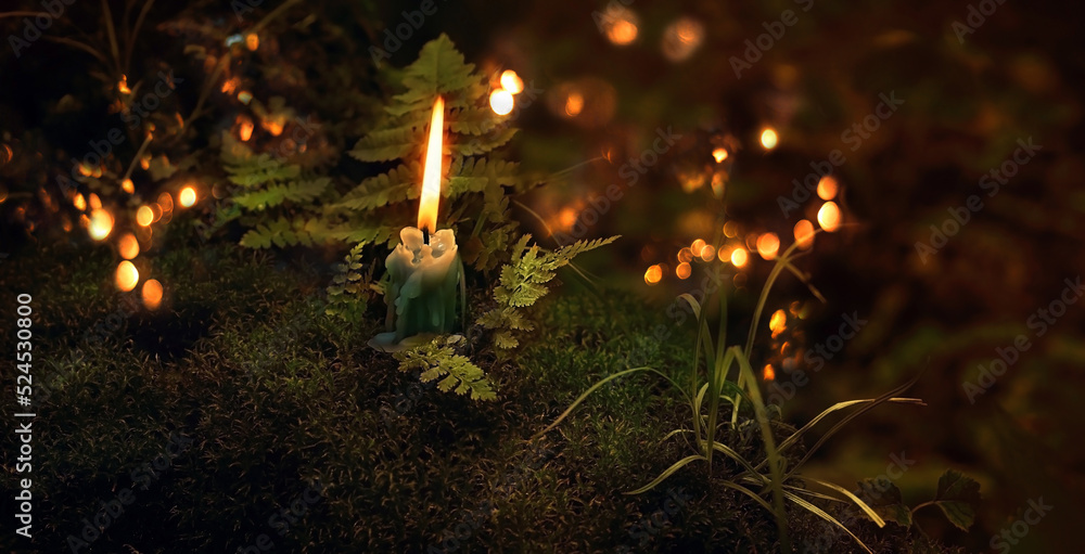 Poster burning candle on moss close up, dark blurred mystery natural background. magic candle for witch rit