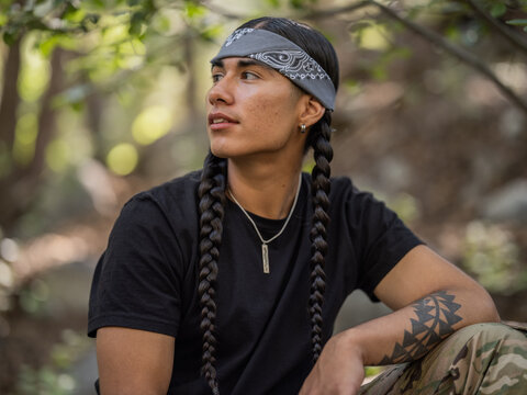Horizontal portrait of an Indigenous man looking to his right with his elbow on his knee