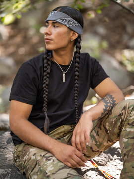Vertical side profile image of an Indigenous man in a forest