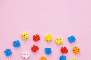 Colored wooden figures in the form hand with smiles on a pink background