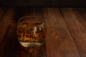  liquor glasses of whiskey, rum, etc., glass tumbler with ice cubes wooden table with glass reflection, text space