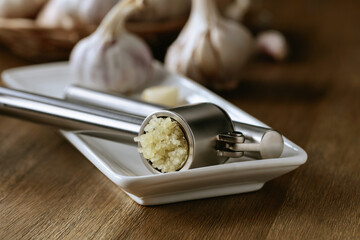 Garlic bulbs and garlic press on a wooden table.