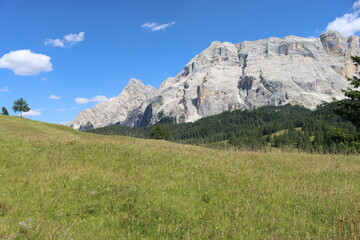 Val Badia, Italy-July 17, 2022: The italian Dolomites behind the small village of Corvara in summer days with beaitiful blue sky in the background. Green nature in the middle of the rocks.