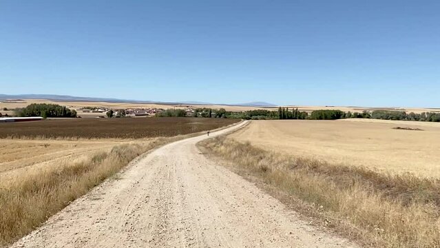 Unrecognizable cyclist on mountain bike rides away on a sloping dirt road. Concept sport in nature