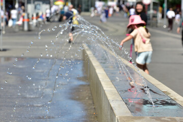 Ein Mädchen kühlt sich an einem Wasserspiel in Wien (Bezirk Favoriten) ab