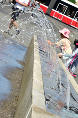 Ein Mädchen kühlt sich an einem Wasserspiel in Wien (Bezirk Favoriten) ab