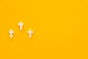 Christian cross on yellow background, top view with space for text. Religion concept