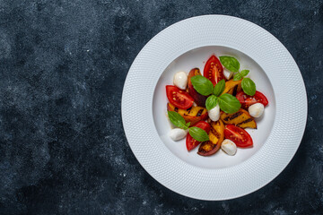 Grilled peach salad with mozzarella, tomato, green basil and sauce, close up, top view