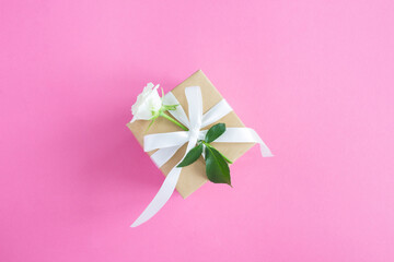 Gift box and with white rose on the pink background.Top view. Copy space.