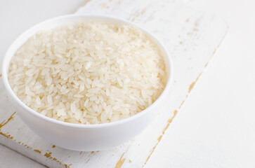Dry camollino rice in a white ceramic bowl on an old kitchen board. The concept of healthy eating. Copy space. Selective focus. Horizontal orientation.