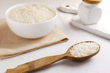 Dry camollino rice in a wooden spoon and a white bowl on a white background. The concept of healthy eating. Horizontal orientation. Rustic style.