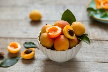 Ripe juicy apricots in a white bowl on a wooden background