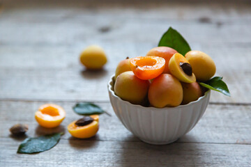 Ripe juicy apricots in a white bowl on a wooden background